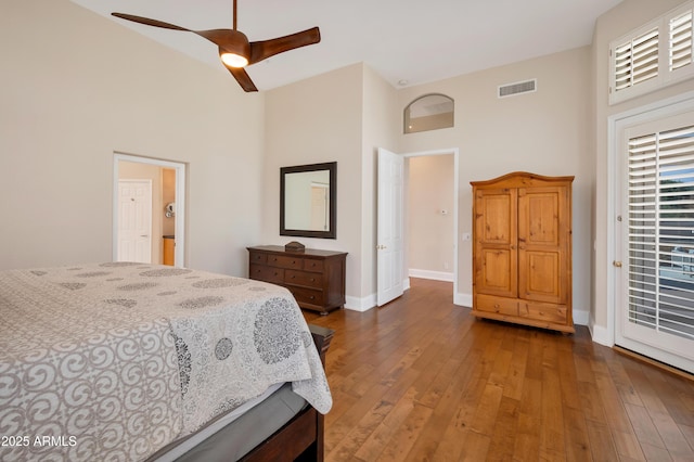 bedroom with visible vents, a towering ceiling, hardwood / wood-style floors, ceiling fan, and baseboards