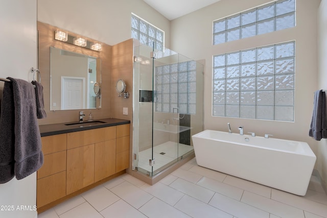 full bath with a stall shower, a soaking tub, tile patterned flooring, and vanity