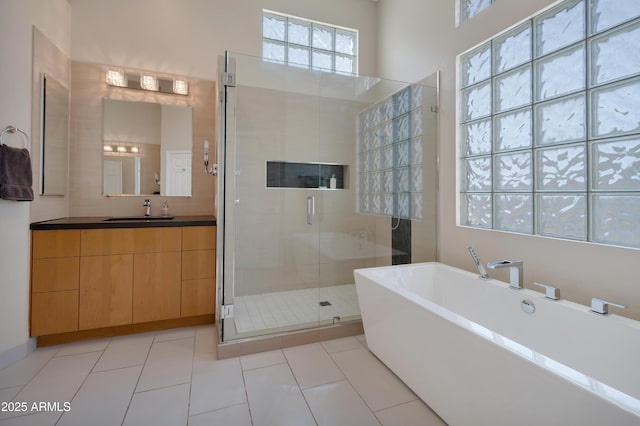 full bath with a stall shower, a soaking tub, tile patterned flooring, and vanity