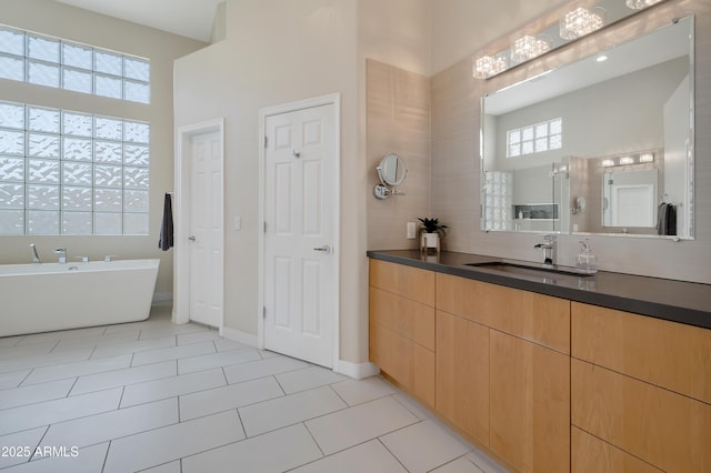 bathroom featuring a high ceiling, a soaking tub, tile patterned flooring, and vanity