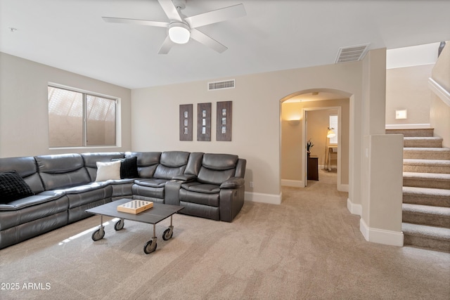 living area with stairway, carpet, visible vents, and arched walkways