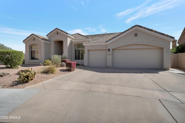 mediterranean / spanish-style house with a garage, driveway, a tile roof, and stucco siding