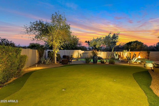 yard at dusk featuring a fenced backyard