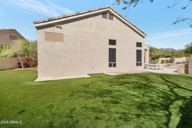 rear view of house featuring fence, a lawn, and stucco siding