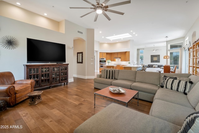 living area featuring visible vents, arched walkways, a ceiling fan, wood finished floors, and recessed lighting