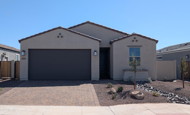 view of front of home featuring a garage, decorative driveway, fence, and stucco siding