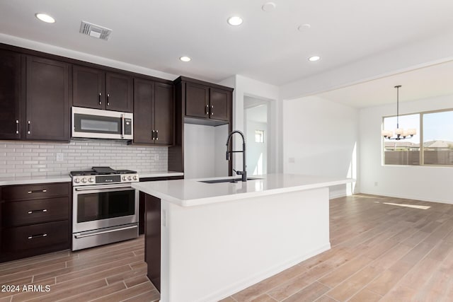 kitchen featuring a center island with sink, wood-type flooring, sink, and appliances with stainless steel finishes