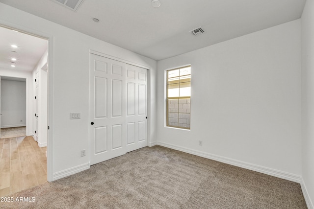 unfurnished bedroom featuring light colored carpet and a closet