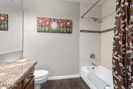 full bathroom with hardwood / wood-style floors, vanity, shower / bath combo, and toilet