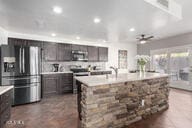 kitchen featuring ceiling fan, stainless steel appliances, a kitchen island with sink, and dark brown cabinets