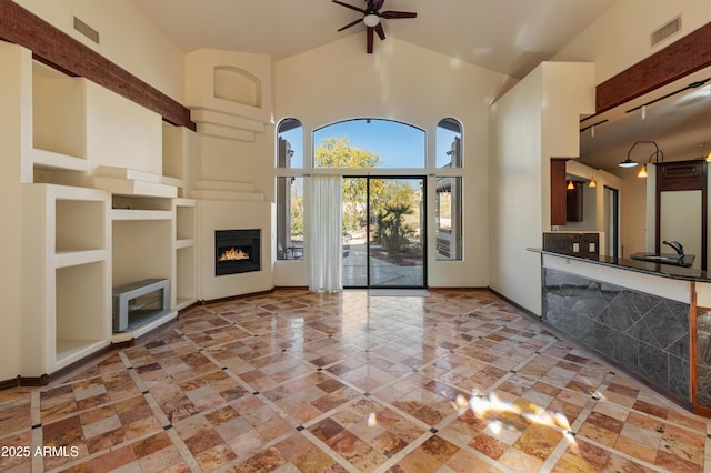 unfurnished living room featuring ceiling fan, sink, and high vaulted ceiling