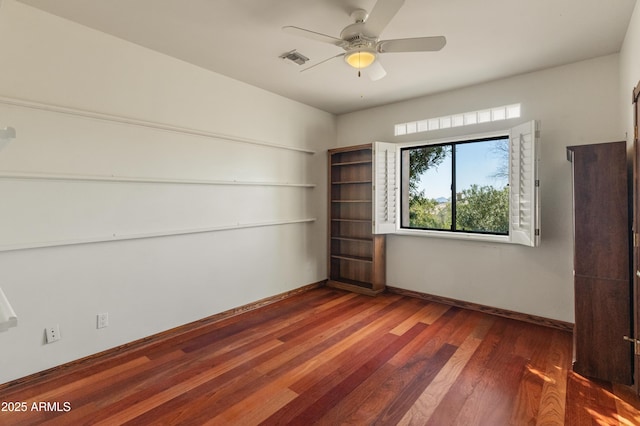 empty room featuring dark wood-type flooring and ceiling fan