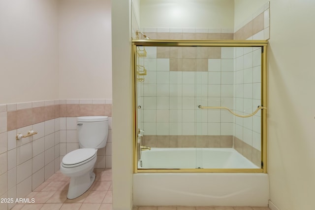 bathroom featuring tile walls, tile patterned flooring, shower / bath combination with glass door, and toilet