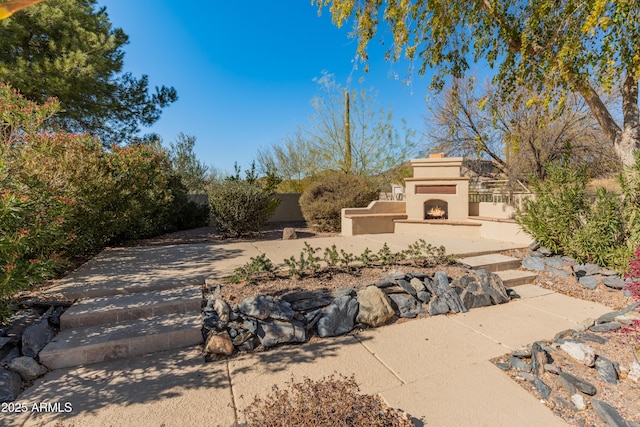 view of yard with an outdoor fireplace and a patio