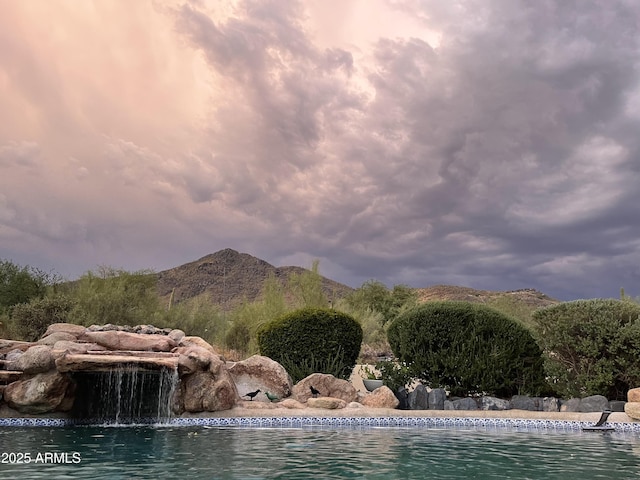 pool at dusk with a water and mountain view