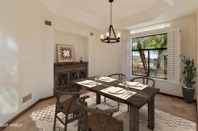 dining space featuring light tile patterned flooring, a notable chandelier, and a tray ceiling