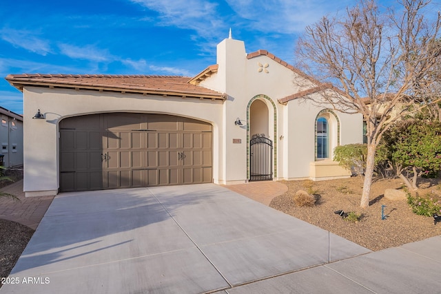 mediterranean / spanish home with driveway, a tiled roof, an attached garage, and stucco siding