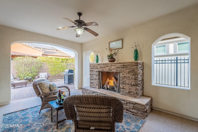 living area with a ceiling fan and a fireplace