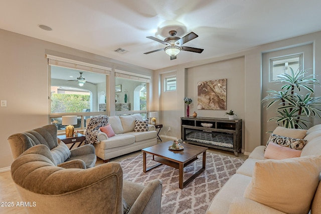 living room with ceiling fan, visible vents, and baseboards