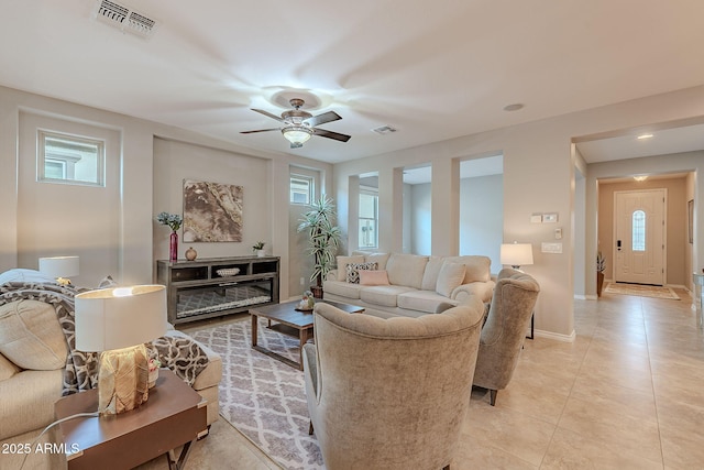 living area featuring visible vents, ceiling fan, baseboards, and light tile patterned floors