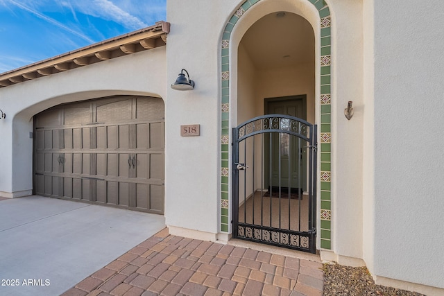 view of exterior entry featuring a gate and stucco siding