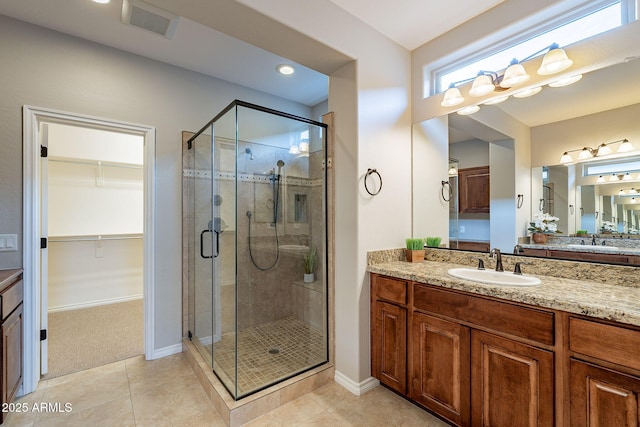 full bathroom with tile patterned flooring, visible vents, vanity, a spacious closet, and a stall shower