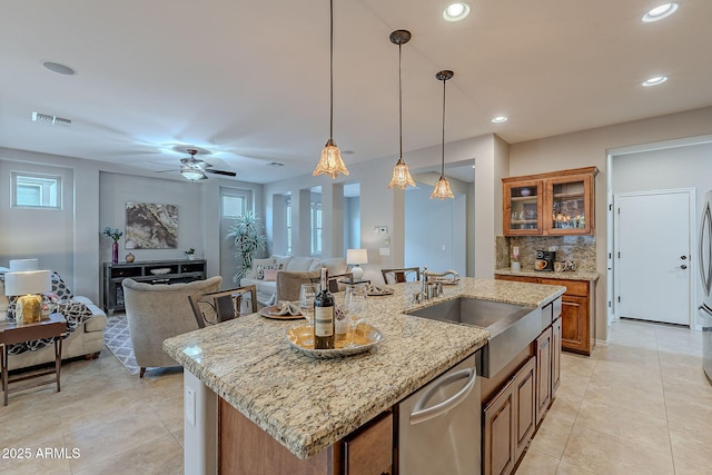 kitchen featuring an island with sink, brown cabinets, glass insert cabinets, and open floor plan