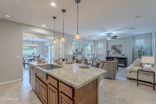 kitchen featuring a center island with sink, brown cabinetry, open floor plan, hanging light fixtures, and a sink