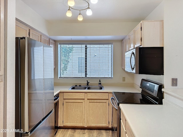 kitchen featuring light brown cabinetry, sink, stainless steel appliances, and light hardwood / wood-style floors