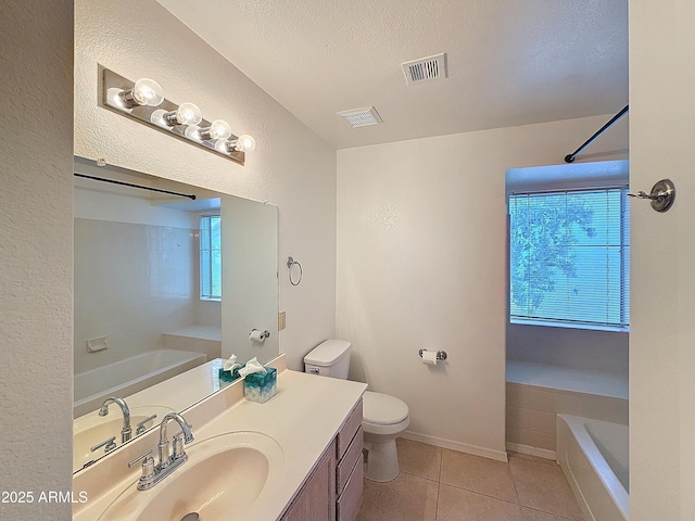 bathroom featuring a tub, vanity, toilet, tile patterned floors, and a textured ceiling