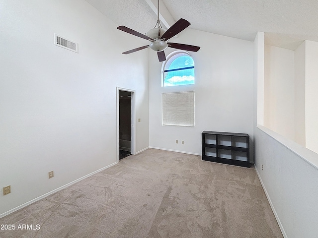 carpeted empty room with ceiling fan, high vaulted ceiling, and a textured ceiling