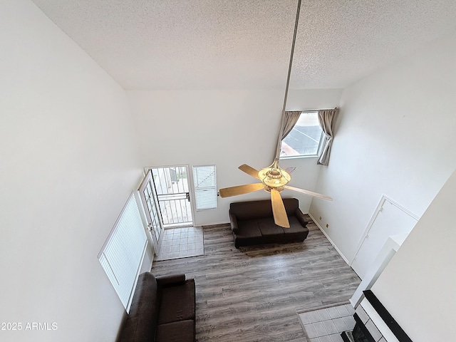 staircase with ceiling fan, wood-type flooring, and a textured ceiling