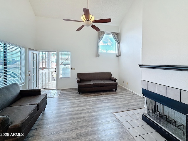 living room with a textured ceiling, high vaulted ceiling, ceiling fan, and light wood-type flooring