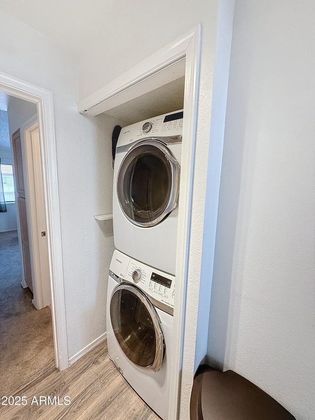 clothes washing area featuring stacked washer / dryer and light hardwood / wood-style floors