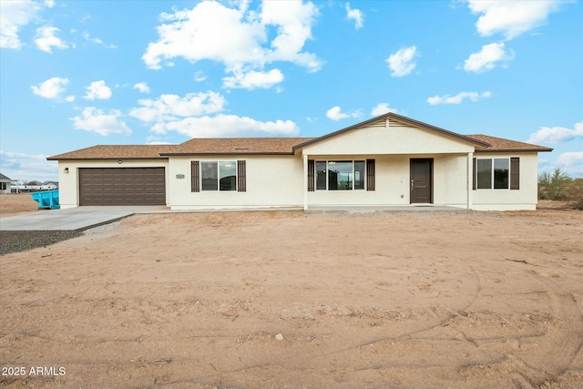 ranch-style home featuring an attached garage, concrete driveway, and stucco siding