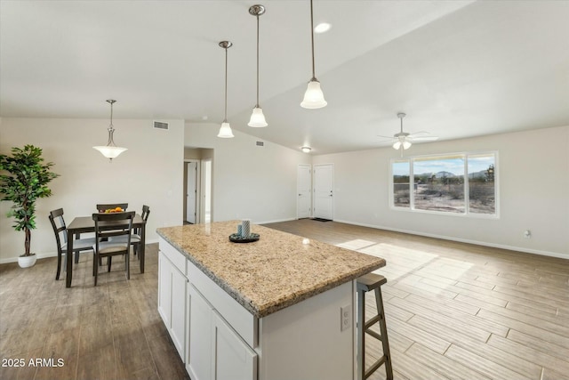 kitchen featuring lofted ceiling, visible vents, a kitchen island, and light wood-style flooring