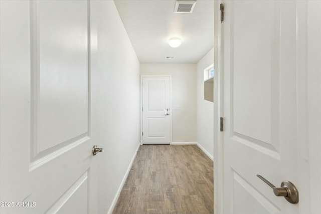 hallway featuring baseboards, visible vents, and light wood-style floors