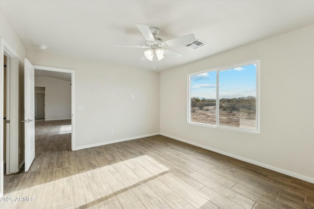 spare room with baseboards, visible vents, ceiling fan, and wood finished floors