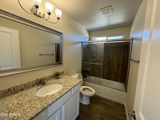 full bath featuring a textured ceiling, toilet, visible vents, vanity, and combined bath / shower with glass door