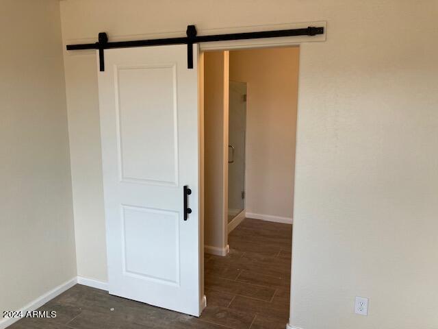 interior space featuring dark wood finished floors, baseboards, and a barn door