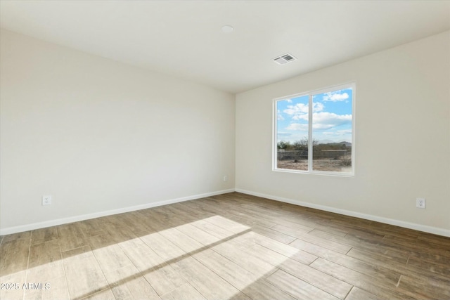 unfurnished room featuring visible vents, baseboards, and wood finished floors