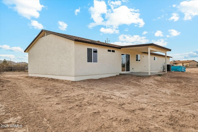 rear view of house with a patio, fence, and stucco siding