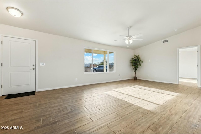 empty room with a ceiling fan, visible vents, vaulted ceiling, and wood finished floors