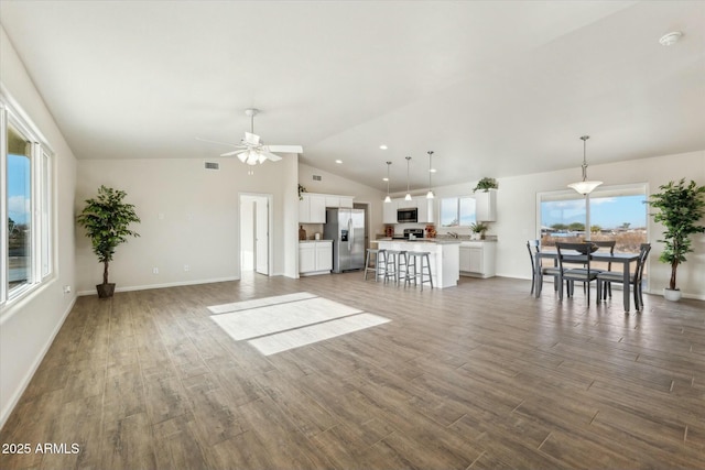 unfurnished living room with lofted ceiling, baseboards, visible vents, and wood finished floors