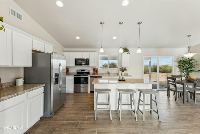 kitchen featuring stainless steel appliances, lofted ceiling, visible vents, white cabinets, and a sink