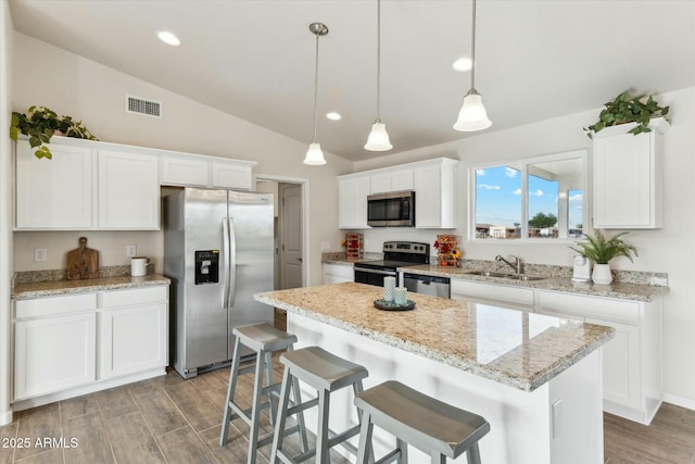 kitchen with visible vents, white cabinets, vaulted ceiling, stainless steel appliances, and a sink