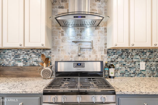 kitchen featuring light stone counters, extractor fan, gray cabinetry, backsplash, and gas stove