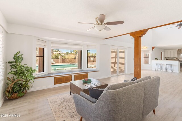 living room featuring ceiling fan, light wood-type flooring, and baseboards