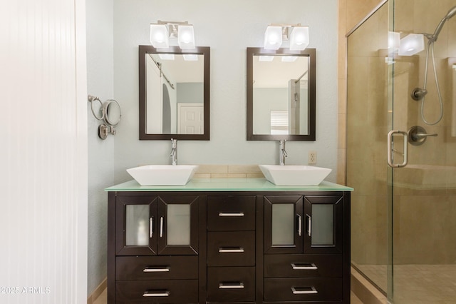 full bath with a stall shower, a sink, and double vanity