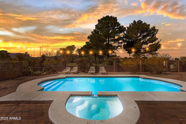 view of pool featuring fence, a fenced in pool, and an in ground hot tub